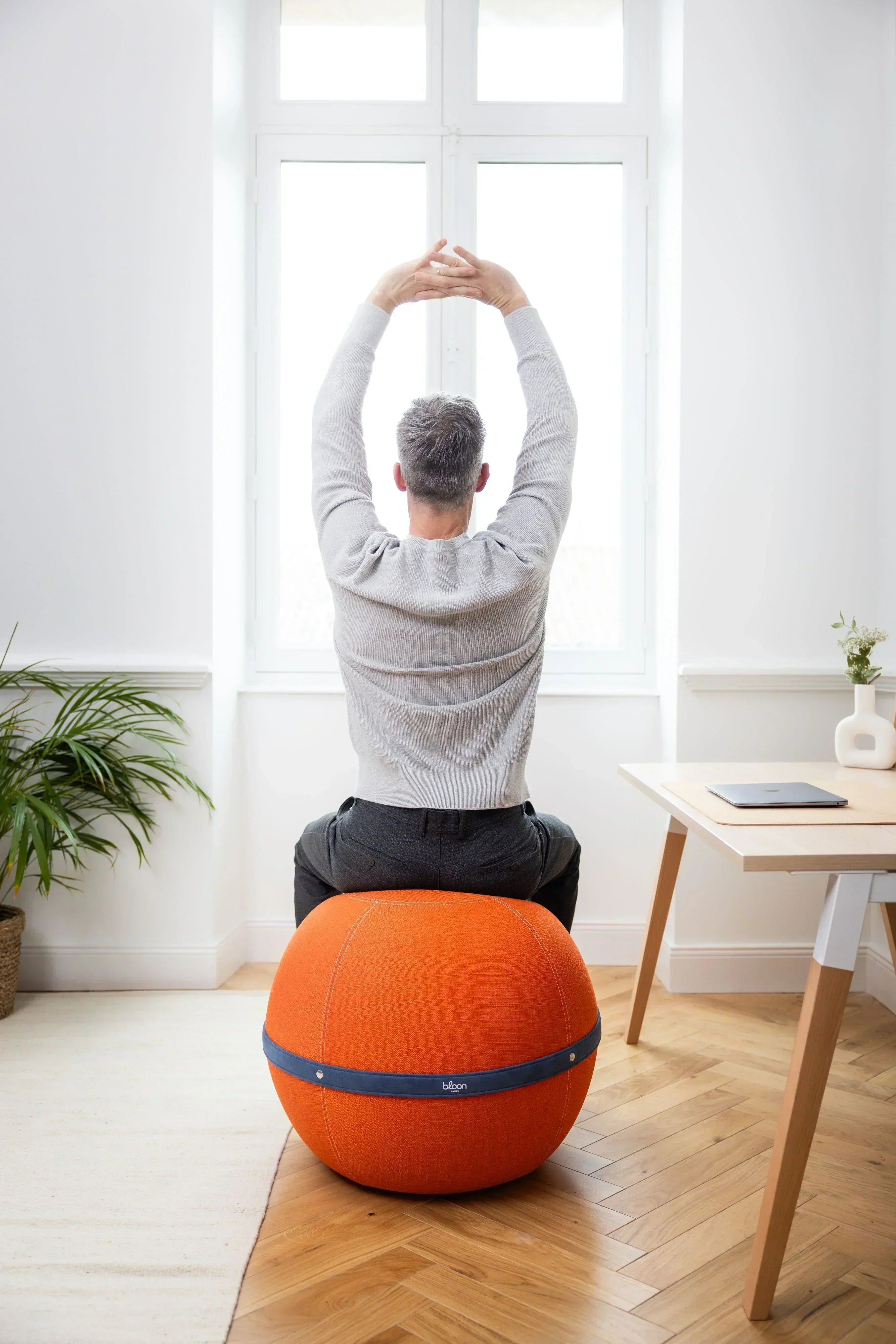 Assise Dynamique : pourquoi remplacer votre assise passive au bureau ? Homme assis sur un siège ballon Bloon orange