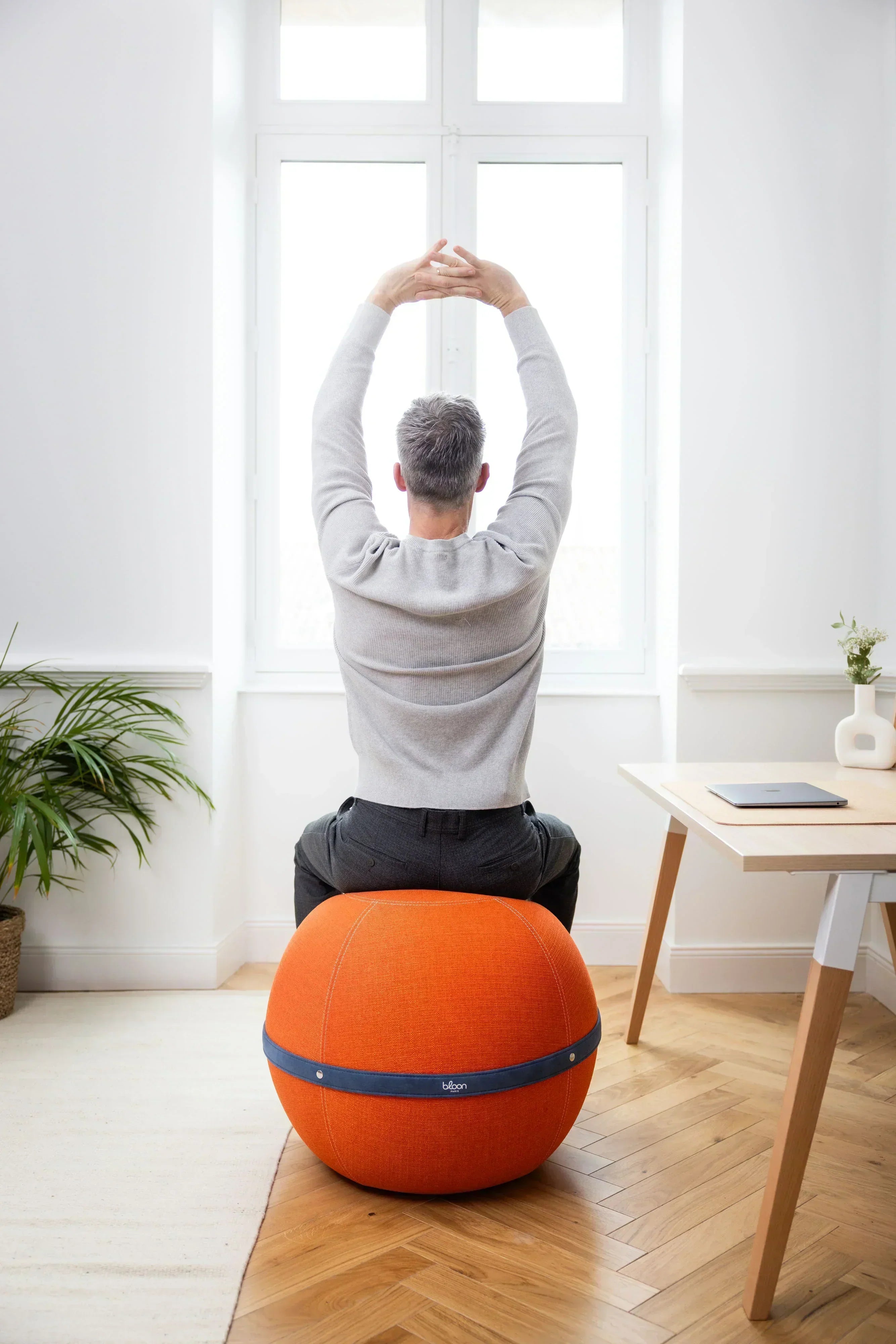 Assise Dynamique : pourquoi remplacer votre assise passive au bureau ? Homme assis sur un siège ballon Bloon orange